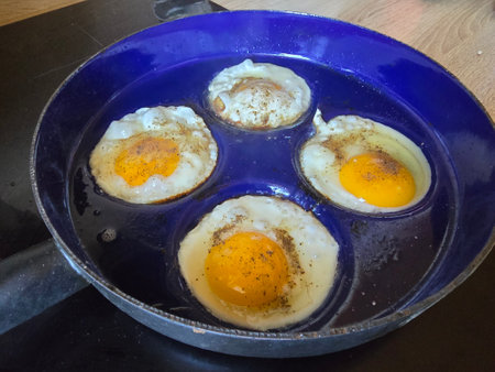 Fried eggs in a frying pan on a wooden table, top viewの写真素材