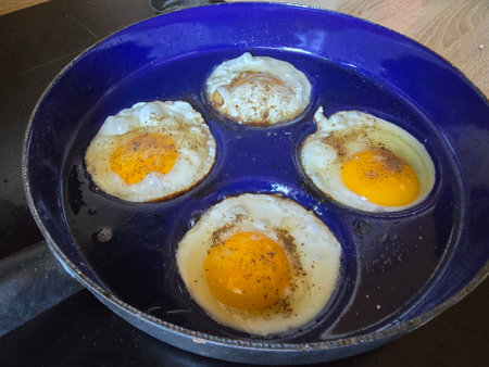 Fried eggs in a frying pan on a wooden table, top viewの写真素材