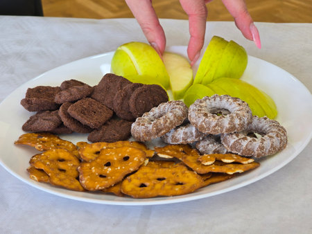 Apples and oatmeal cookies on a white plate with a woman's handの写真素材