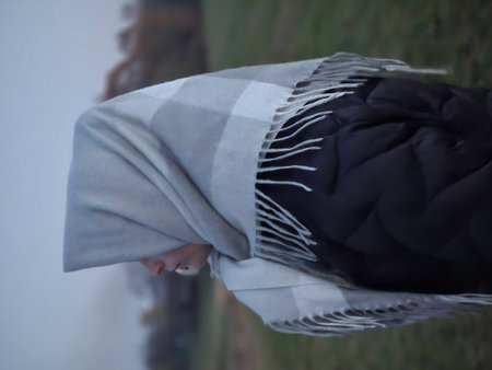 A young woman wearing a white shawl is walking in the rain.の写真素材