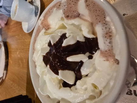 A cup of coffee with whipped cream and chocolate in a cafe.の写真素材