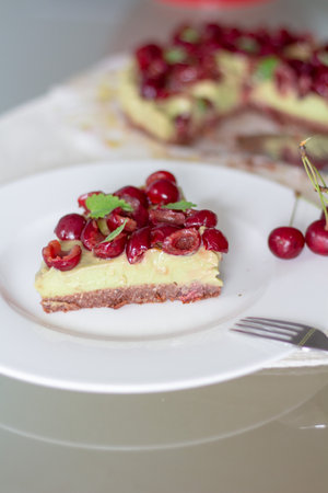 Cherry cheesecake with fresh cherries on a white plate.の写真素材