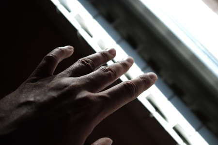 caucasian tanned human hand near the window, dark and light, mystery, exit, end of tunnel, hope. Persuasion, tempting, temptationの写真素材