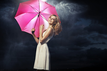 Cheerful blonde woman with the pink umbrellaの写真素材