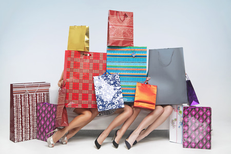 Three women under the plenty of shopping bagsの写真素材
