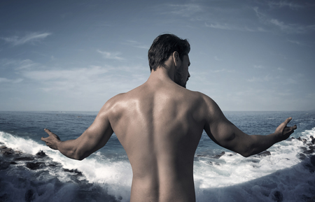 Portrait of a muscular guy posing over the oceanの写真素材