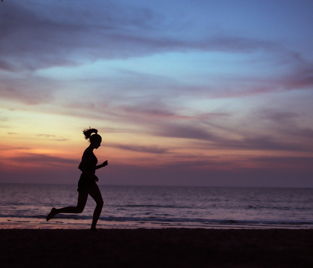 Young, athletic woman jogging on a beach during the susnetの写真素材