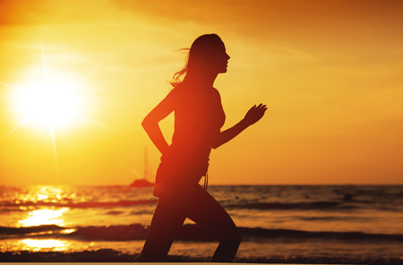 Young athletic woman running on a tropical beachの写真素材