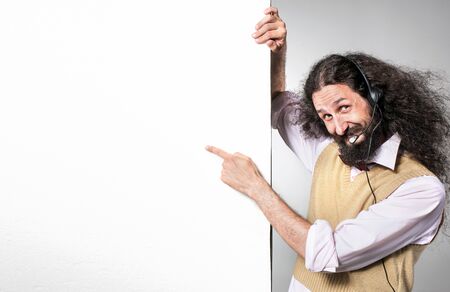 Portrait of a nerdy telemarketer pointing on an empty, commercial boardの写真素材