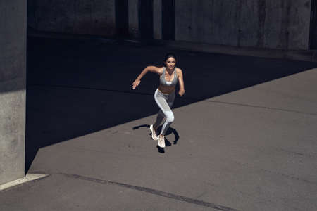 Portrait of a brunette, young athlete sprinting in tunnel