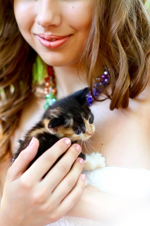 Pretty young caucasian girl with kitten on her handsの写真素材