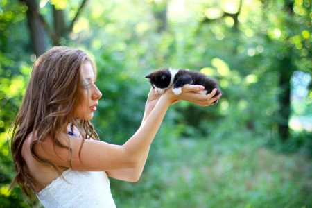 Pretty young caucasian girl  with cute kitten on her handsの写真素材