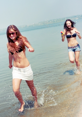 Happy young women playing at the beach の写真素材