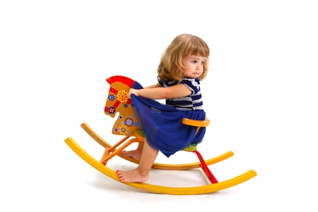 Babe riding on toy wooden horse and looking backの写真素材