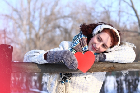 Dreaming winter girl holding red heart outdoorsの写真素材