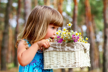 Little girl smelling a daisy in  summer forestの写真素材