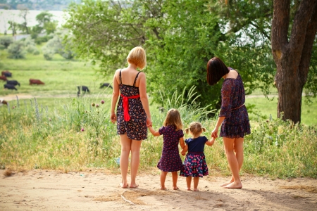 Two mothers with their daughters on  summer field, rear viewの写真素材
