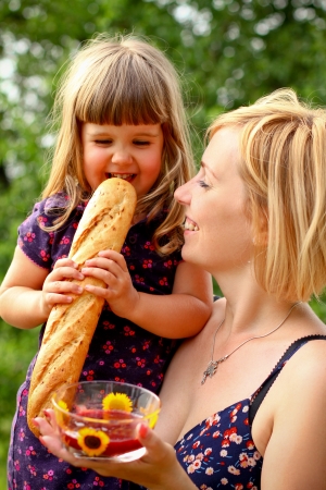 Mother and daughter with jam and a bread outdoorsの写真素材