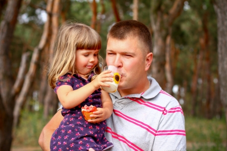 Picnic in  woods, daughter giving of her father  milkの写真素材