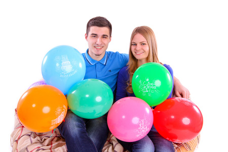 Friends sitting on a sofa with balloons isolatedの写真素材