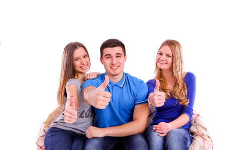 friends sitting on a sofa and making a thumbs up signの写真素材