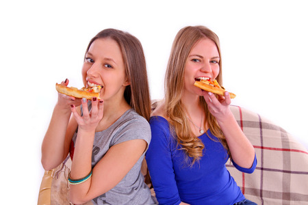 Two girlfriends eating pizza isolatedの写真素材