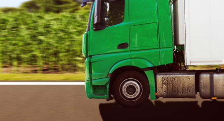 green truck is driving fast on country roadの写真素材
