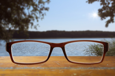 black modern glasses on wooden table with blue sky and lake in the backgroundの写真素材