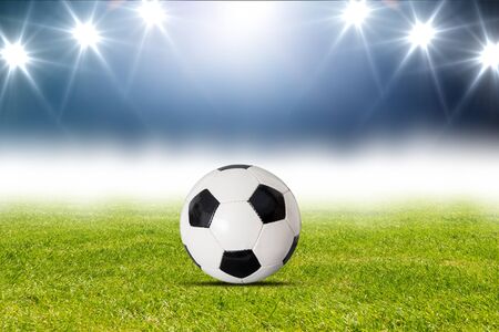 Soccer ball is lying on grass on field at stadiumの写真素材