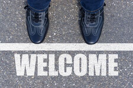 Welcome message on asphalt and business shoesの写真素材