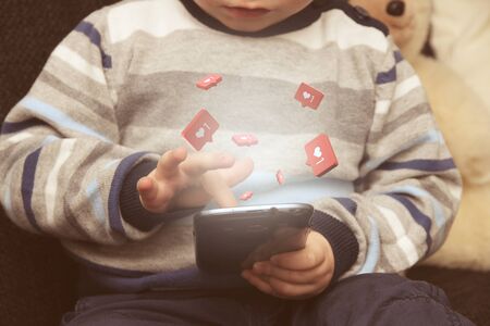 Young child is playing with smartphone and gets likesの写真素材