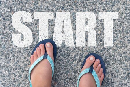 Top view of bare feet in flip-flops on the floor with the text: START