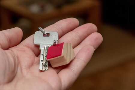 Hand holding key with wooden house shaped key chain