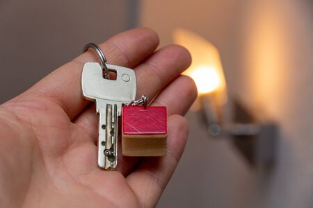 Hand holding key with wooden house shaped key chain