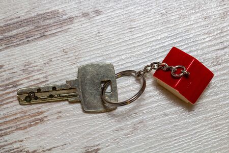 Key with house shaped key chain on white wooden background