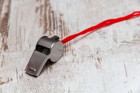Metal whistle on white wooden background