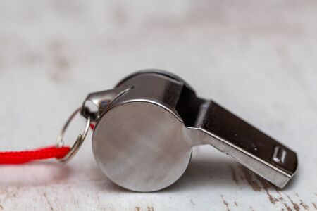 Metal whistle on white wooden background, closeup photo