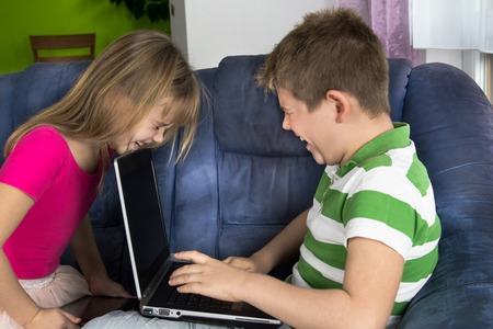 Children are looking at the computer and tablet together.の写真素材