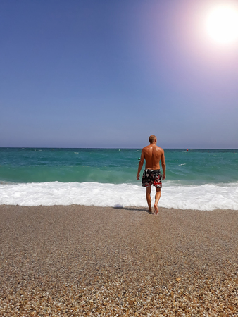 Back view of relaxed young muscular man enjoying sea view.の写真素材