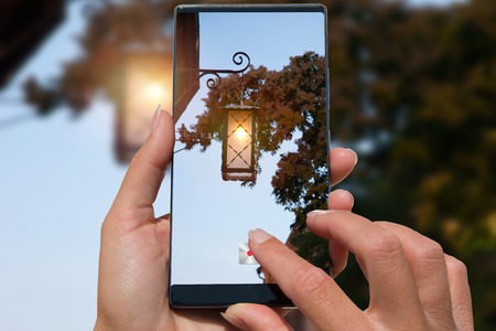 Woman takes pictures on a mobile old lantern on the house.の写真素材