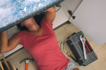 Beautiful handywoman woman fixing kitchen sink.の写真素材