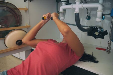 Beautiful handywoman woman fixing kitchen sink.の写真素材