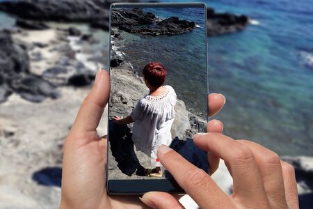 Woman photographing on cell phone happy elderly woman on beach.