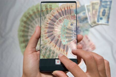 Woman photographing on cell phone Vietnamese money (Dong)の写真素材