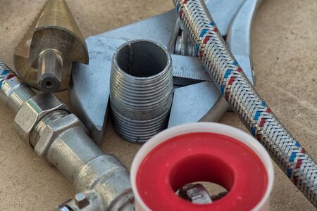 Different things for plumbers lie on ground. Teflon tape, wrench, hose, tube, water tap .の写真素材
