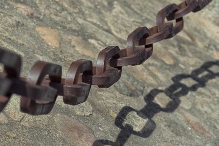 Detail view of vintage rusty chain on the stone ground.