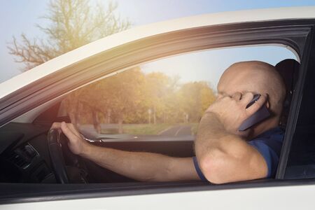 Man driving in car and talking on cell phone. Holiday, vacation, road trip.の写真素材