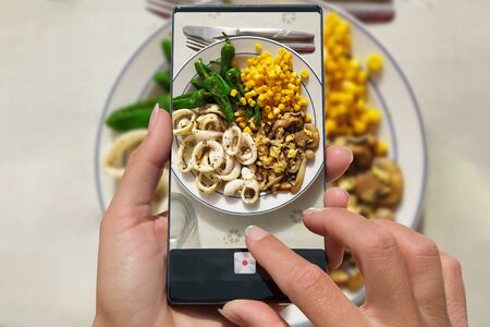 Woman photographing on cell phone homemade food.