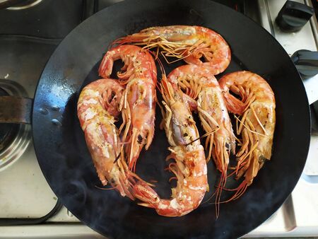 Close-up of hot steaming pan with fried shrimps.の写真素材