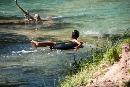 Boy floating down a river in a blow up tube.の写真素材
